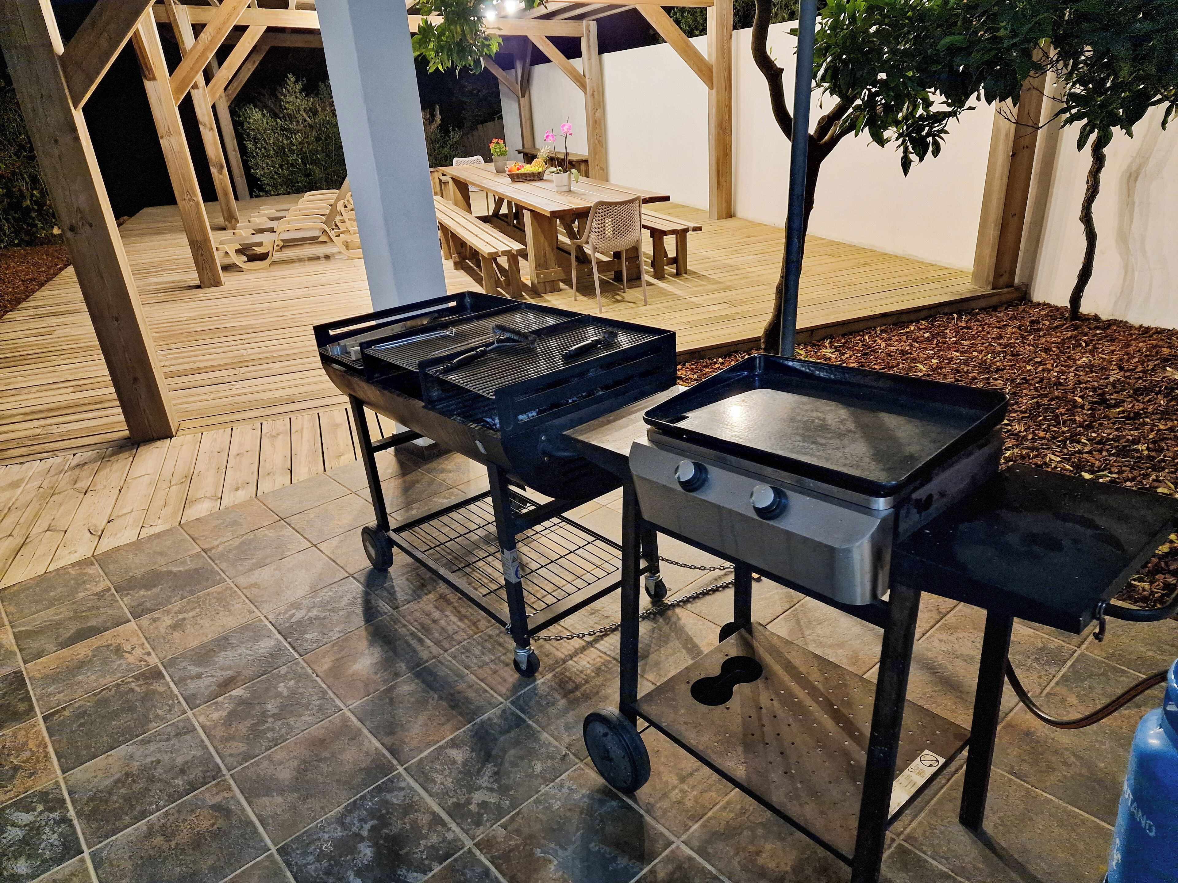 Une terrasse extérieure équipée d’un barbecue et d’une table aménagée pour les repas.