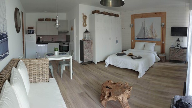 Quarto moderno e bem iluminado, com cama, mesa de jantar e cozinha compacta.