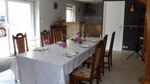 Un espace repas avec une longue table dressée pour six personnes, entourée de chaises en bois.