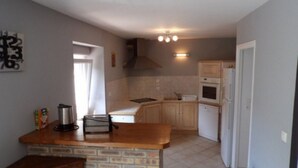Une cuisine compacte dotée d’un îlot central, de meubles en bois, d’un four encastré et d’un petit évier.