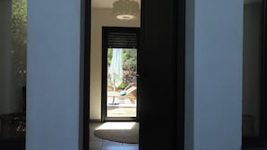 Un couloir mène à une porte qui donne sur un espace extérieur aménagé avec un toboggan et une piscine.
