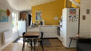 A compact kitchen with a dining area, wooden flooring, and a yellow accent wall. - Maison pieds dans l'eau, vue mer dans une calanque 83220 Le PRADET ( Var) (Le Pradet)
