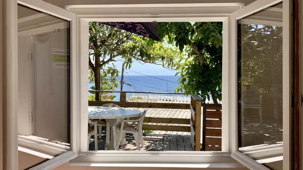 A room with a view of the sea, a table with chairs, and a wooden deck. - Maison pieds dans l'eau, vue mer dans une calanque 83220 Le PRADET ( Var) (Le Pradet)