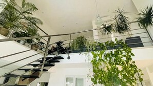 Ein mehrgeschossiges Interieur mit einer Treppe, mehreren Blumentöpfen und einer hängenden Pflanze.