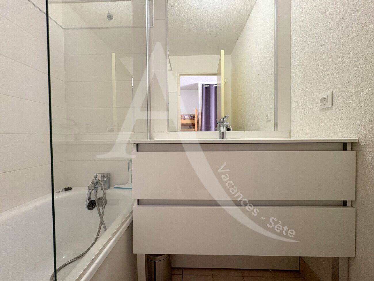 Un baño con cabina de ducha de vidrio, una bañera blanca y un tocador con espejo.