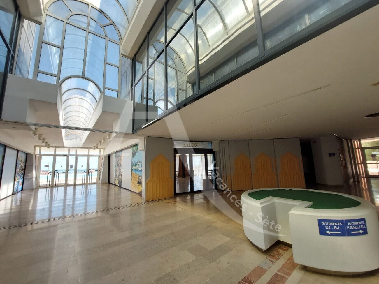 A spacious lobby with a high ceiling, large windows, and a reception desk.