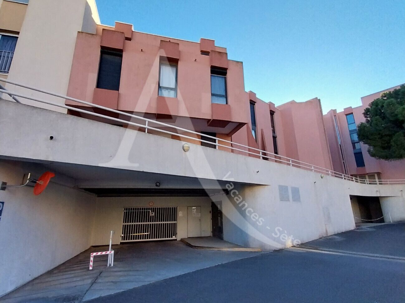 Un edificio de varios pisos con techo plano, entrada cubierta y zona de estacionamiento cerrada.