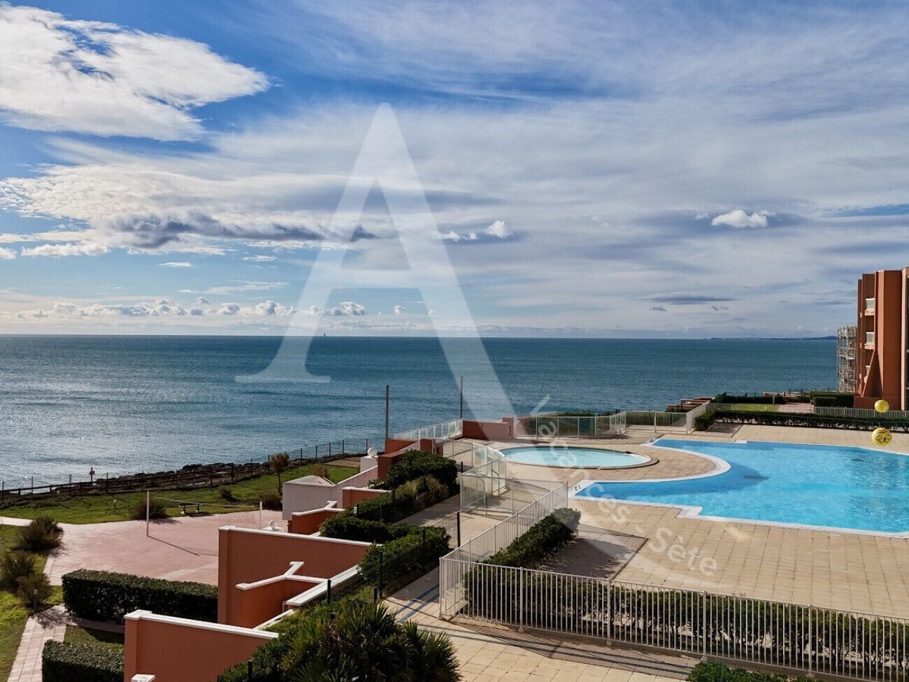 A resort with a pool area, a view of the sea, and a building with balconies.