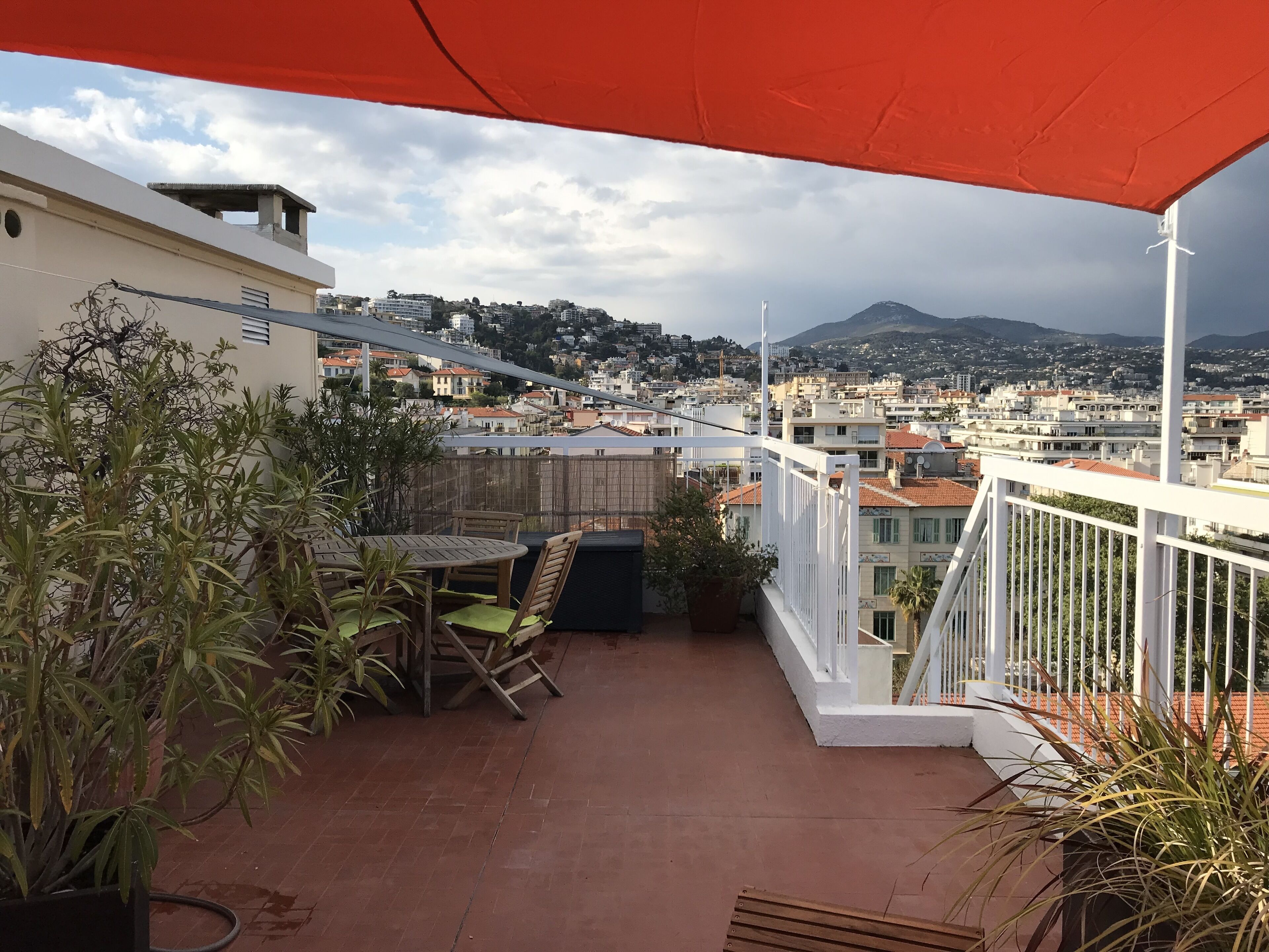 A balcony with a view of a cityscape, including buildings and a mountain.