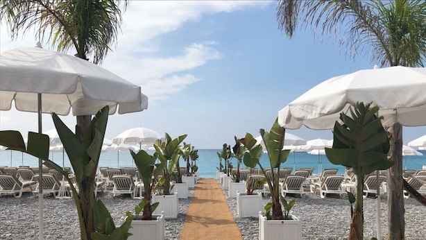 Une promenade en bord de mer, agrémentée de parasols et de chaises longues, qui mène à la mer.