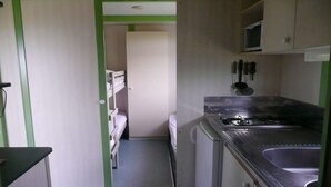 A compact kitchen with a gas stove, a microwave, and basic utensils. A bunk bed is visible in the adjacent room. - panoramic sea view chalet, chalet club 8 (Plomodiern)