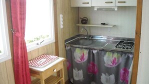 Una cucina compatta con fornello a gas, lavandino e un piccolo tavolo con tovaglia a scacchi.
