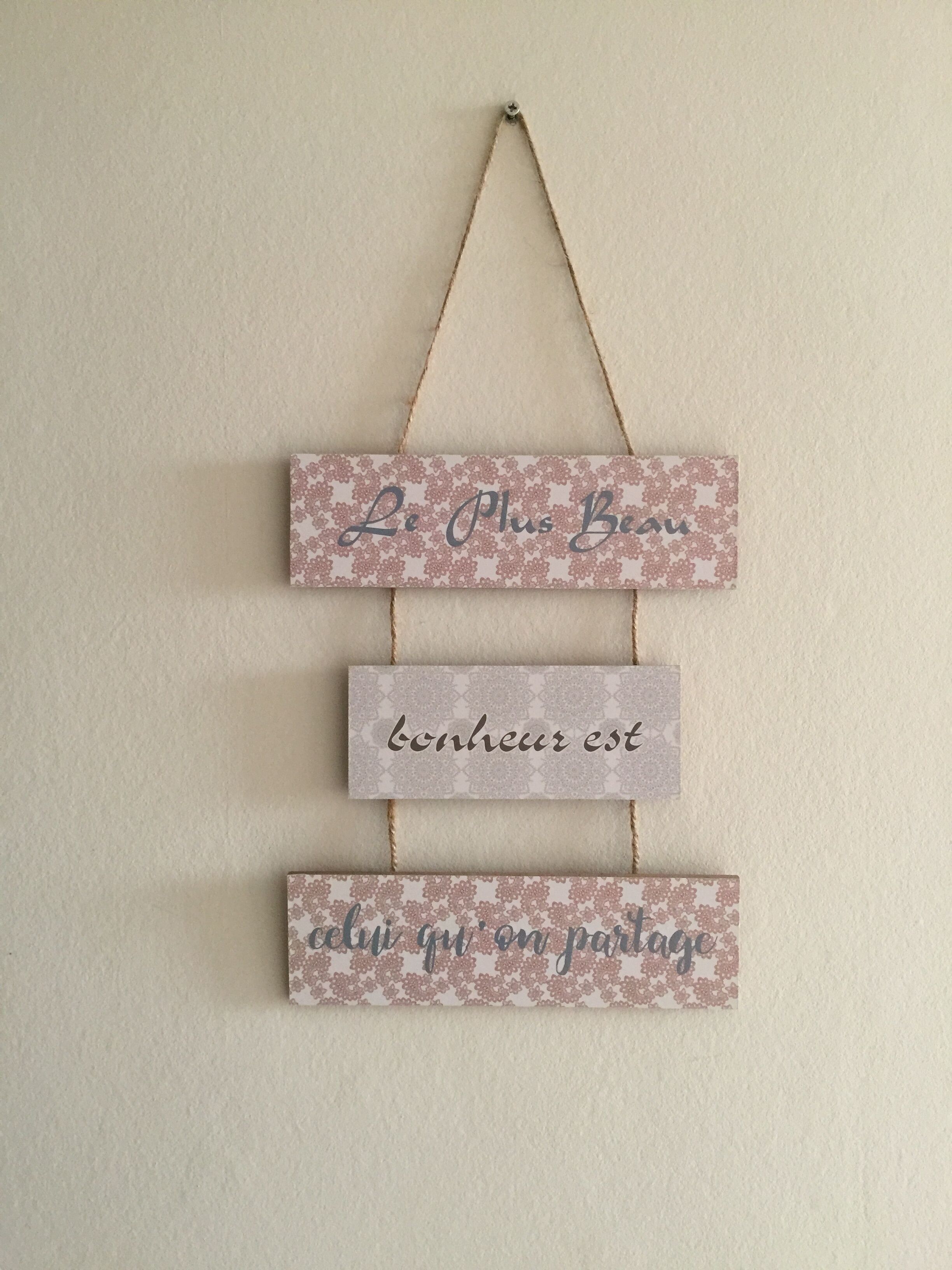 A wall-mounted decoration with three rectangular panels, each with text and a floral pattern.