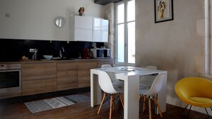 Eine moderne Küche mit Holzausstattung, einem weißen Esstisch und einem gelben Stuhl.