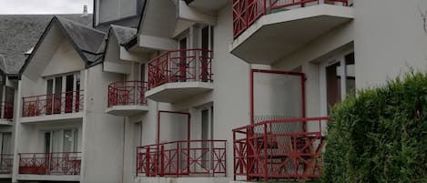 A multi-story building with balconies, a parking sign, and a gated entrance.