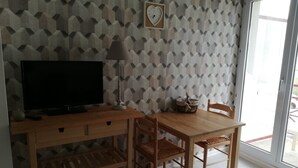A room with a TV on a wooden desk, a lamp, and a chair. - very nice studio DINARD / LA RICHARDAIS 5 minutes from the beach (LA RICHARDAIS)