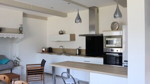 Eine moderne Küche mit einer Holztheke, Edelstahlgeräten und Pendelleuchten.