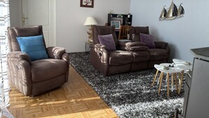 A living room with a brown leather sofa, a wooden coffee table, and a patterned rug. - The lodge "L'Allée du Val" (Lalaye)