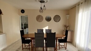 A dining area with a round table, six chairs, a wall clock, decorative mirrors, and a ceiling light fixture. - House with private pool and garden (Nyons)