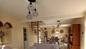 A living room with a sofa, a coffee table, and a staircase leading to a dining area. - House with private pool and garden (Nyons)