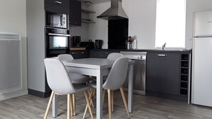 Une cuisine moderne dotée d’un îlot central, d’appareils électroménagers intégrés et d’une fenêtre laissant entrer la lumière naturelle.