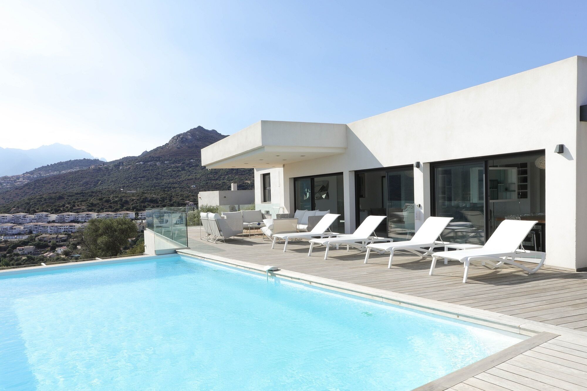 A modern poolside area with lounge chairs and a view of a mountain.
