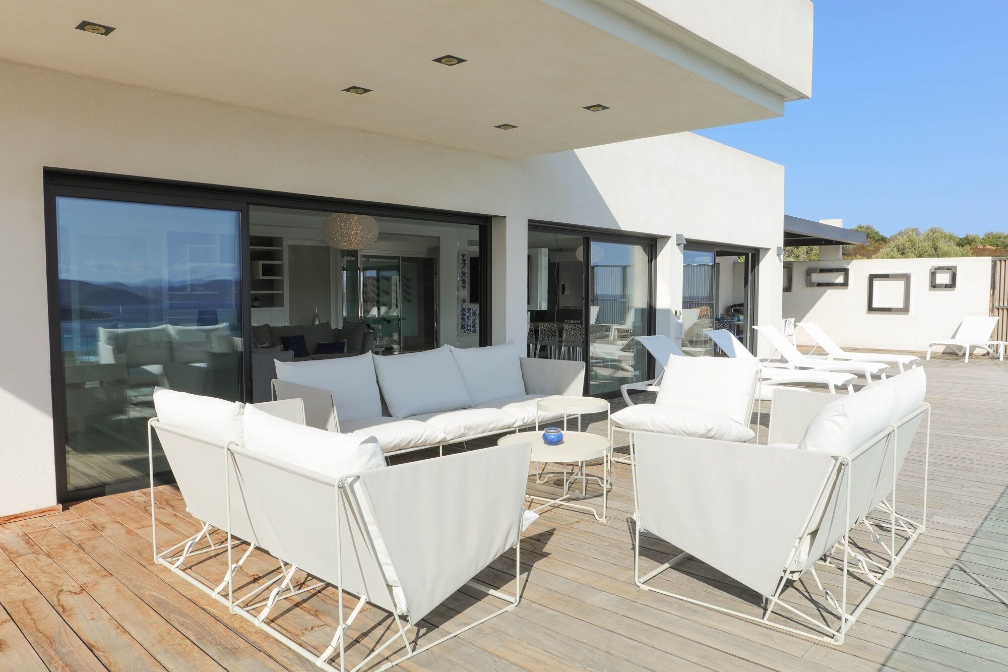 Un espace extérieur moderne aménagé avec des meubles blancs et une terrasse en bois.