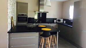 Une cuisine moderne dotée d’un îlot central, de tabourets de bar, d’un four à micro-ondes et d’une cuisinière.