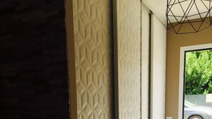 Un couloir aux murs ornés de motifs, une porte donnant sur l’extérieur et un sol carrelé.