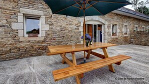 A stone building with a wooden picnic table and umbrella. - ----- Ty Corentin ---- (LA FORET FOUESNANT,)