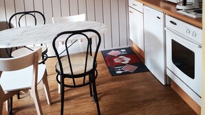A compact kitchen with a wooden floor, white cabinets, a white table, and a clock on the wall. - At the heart of the resort Lioran (Laveissière)