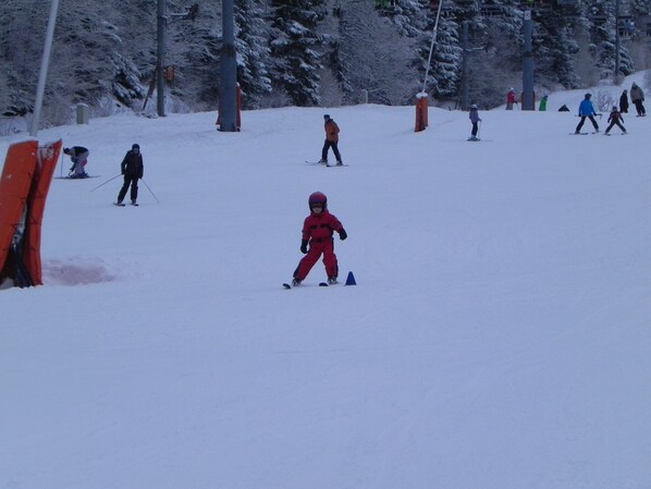 Une piste de ski avec des skieurs et un enfant vêtu de rouge.