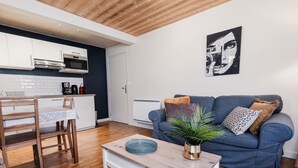 Un espacio moderno de estar con cocina, comedor y un sofá azul con almohadones decorativos.
