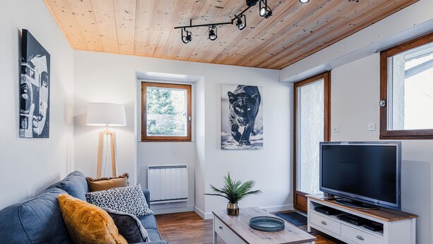 Una sala de estar moderna con un sofá, una mesa de centro, televisión y obras de arte.