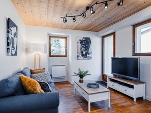 Una sala de estar moderna con un sofá, una mesa de centro, televisión y obras de arte.