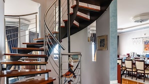 A modern spiral staircase with wooden steps and metal railings, leading to an upper floor. - Villa Serenity (Kymi-Aliveri)