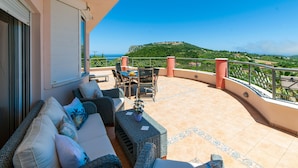 A balcony with outdoor furniture, a view of a hill, and a clear sky. - Villa Serenity (Kymi-Aliveri)