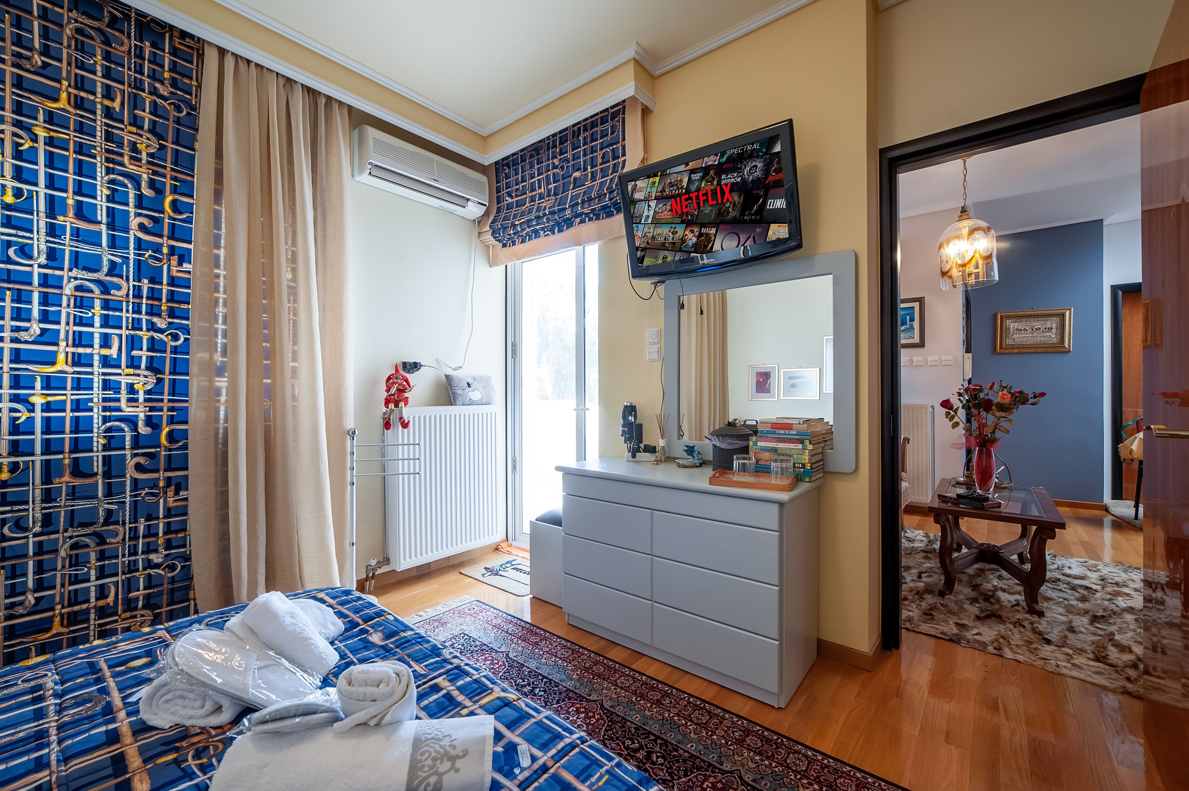 Une chambre d’hôtel avec un lit, une commode, un téléviseur diffusant Netflix et une vue sur l’extérieur.