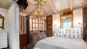 A bedroom with a large bed, wooden wardrobe, and a mirror. - Charming Suite - Le Perchoir (Calvi)