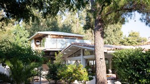 A house with a covered patio, surrounded by trees and potted plants. - Charming Suite - Le Perchoir (Calvi)