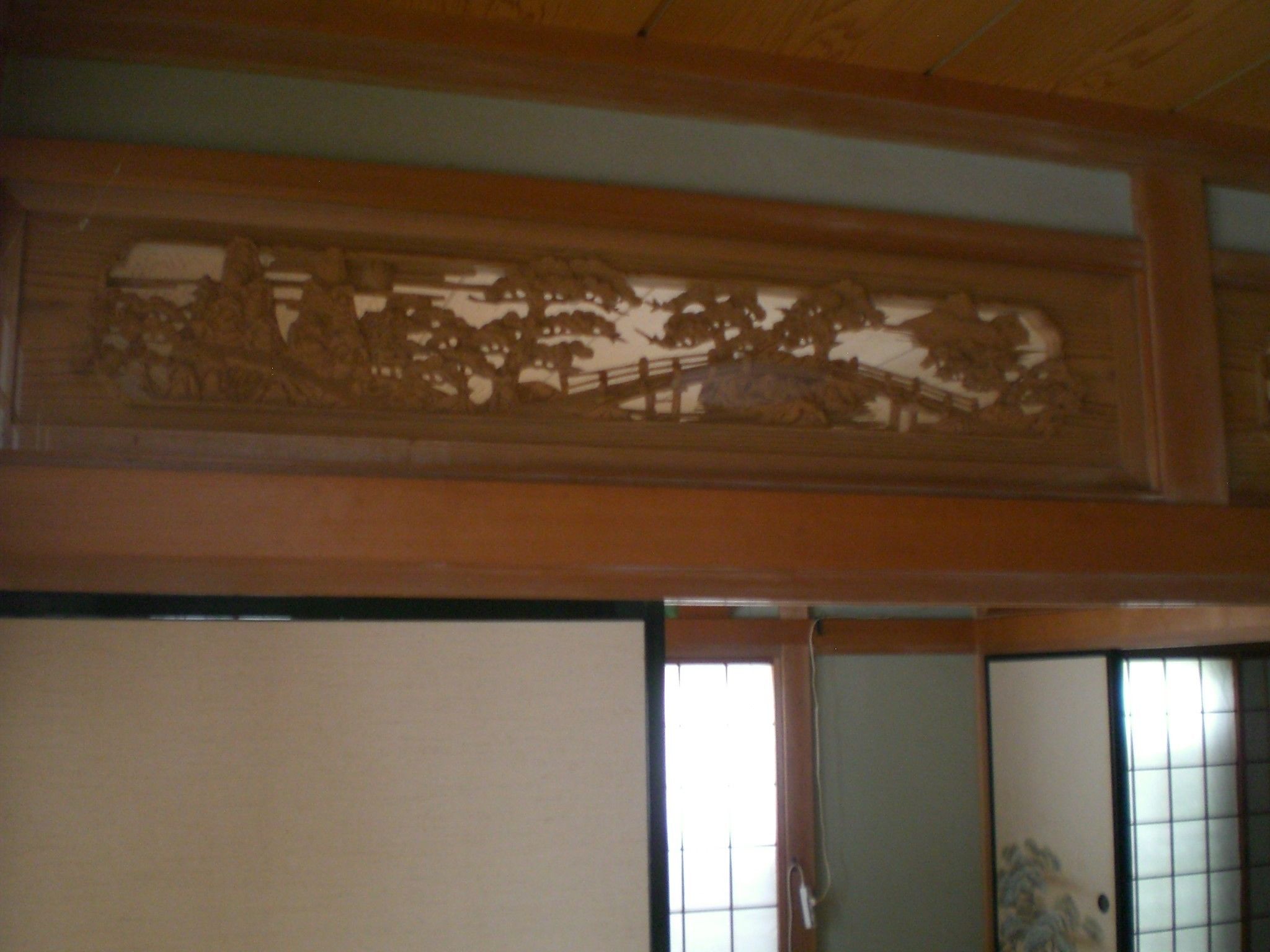 Een traditionele Japanse kamer met tatami vloeren, een shoji schuifdeur en een houten plafond.