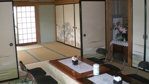 Una habitación japonesa tradicional con suelo de tatami, puertas correderas y una mesa de madera baja con sillas.