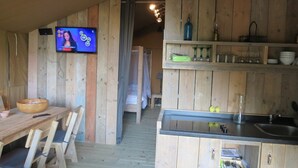 Ein rustikales Holzinterieur mit Essbereich, einem an der Wand montierten Fernseher und einer Küche mit Holzausbau und Spüle.