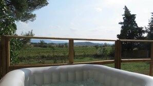 Ein Whirlpool im Freien mit Holzgeländer und Blick auf einen Weinberg.