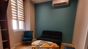 A compact living space with a sofa, a small table with magazines, a blue chair, and a patterned rug. - Apartment 100 refurbished !!!! 07/2019 !!!! 35 M2 (3 beds)   (Bourg-Saint-Andéol)