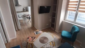 A modern living room with a sofa, a small table, a TV mounted on the wall, and a window with blinds. - Apartment 100 refurbished !!!! 07/2019 !!!! 35 M2 (3 beds)   (Bourg-Saint-Andéol)