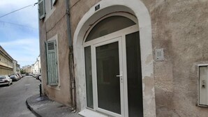 A building with a large arched doorway, a visible number '13' above the entrance, and a narrow street with parked cars. - Apartment 100 refurbished !!!! 07/2019 !!!! 35 M2 (3 beds)   (Bourg-Saint-Andéol)