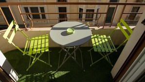 A balcony with a table and two chairs, a railing, and a building in the background. - 🎖 Pretty 3 rooms in the city center (Annecy)