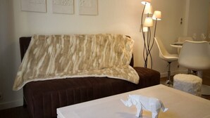 A hotel room with a brown sofa, a white table with a white sculpture, and a floor lamp. - 🎖 Pretty 3 rooms in the city center (Annecy)