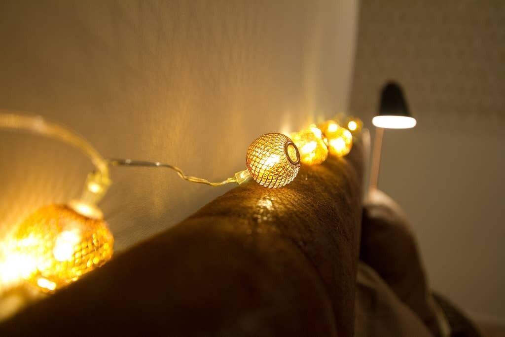 Gros plan d’une guirlande lumineuse avec une ampoule sphérique, qui pourrait faire partie d’un objet décoratif ou d’un meuble.